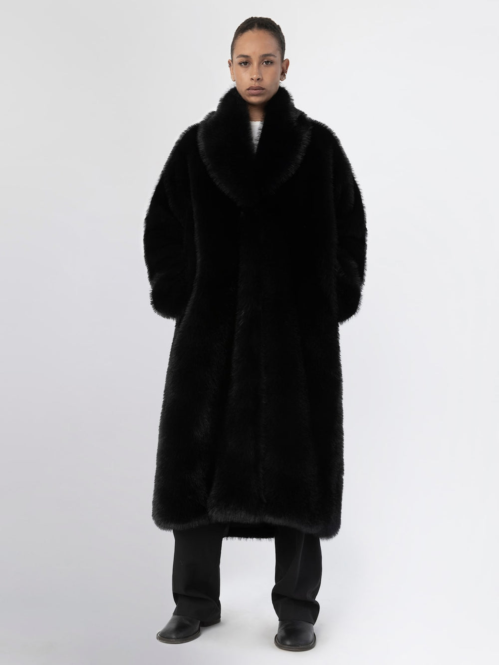 Lang, sort MEOTINE frakke med blødt pelslook og store lommer, perfekt til kolde dage.