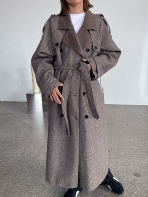 Lang, brun MEOTINE frakke med bælte og klassisk trench coat design, perfekt til efteråret.