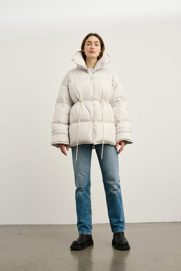 Oversized, lys jakke med snøre i taljen, iført af en model med jeans. MEOTINE tilføjer stil og komfort til din garderobe.