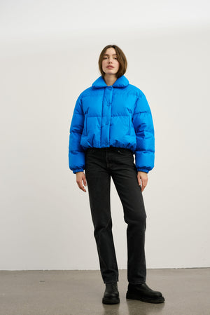 Blå, quilted jakke fra MEOTINE, med kort design og høj krave, stylet med sorte jeans og støvler. Perfekt til en trendy look.