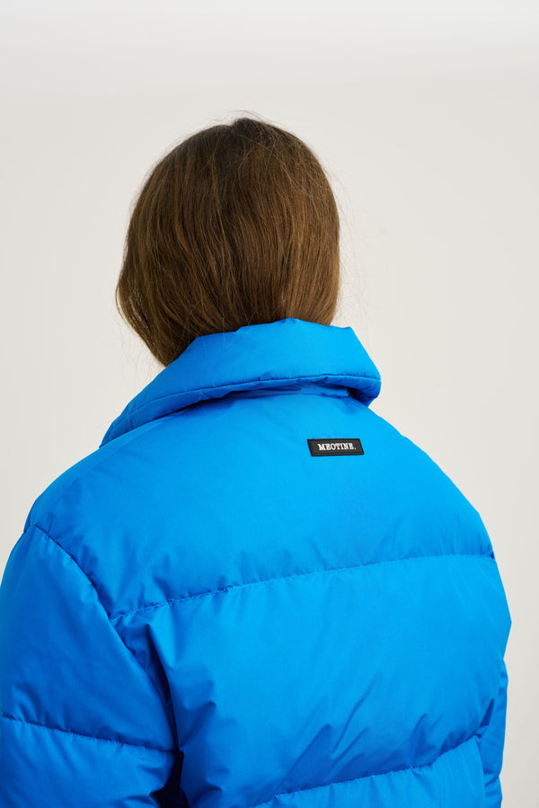 Blå dunjakke med høj krave og MEOTINE-logo på ryggen, set bagfra. Perfekt til kolde dage.