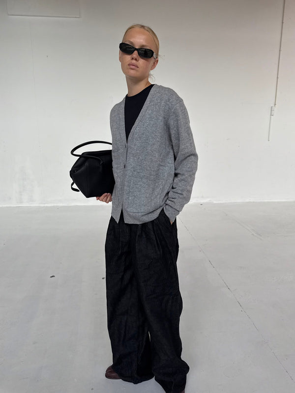 Modellen bærer en grå cardigan og sorte bukser, kompletteret med solbriller og en sort taske fra MEOTINE.
