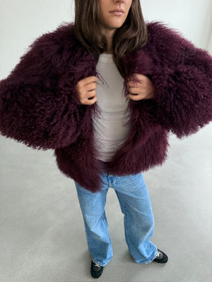 Lækker MEOTINE jakke i dyb bordeaux med fluffy pels, stylet med en hvid top og løse jeans for et afslappet look.