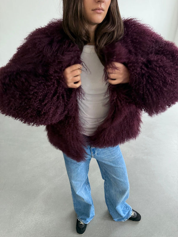 Lækker MEOTINE jakke i dyb bordeaux med fluffy pels, stylet med en hvid top og løse jeans for et afslappet look.