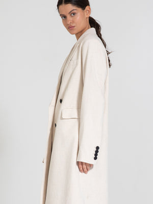 Lang beige frakke fra MEOTINE med lange ærmer og knapdetaljer, perfekt til en stilfuld og moderne garderobe.