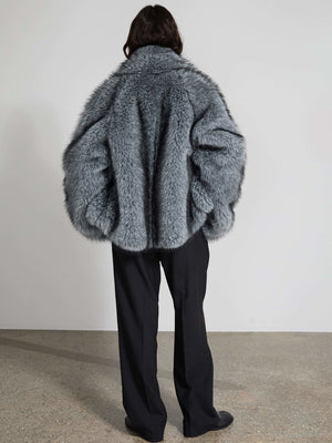 Grå, fluffy jakke fra MEOTINE set bagfra, kombineret med sorte bukser, der skaber et elegant og moderne look.