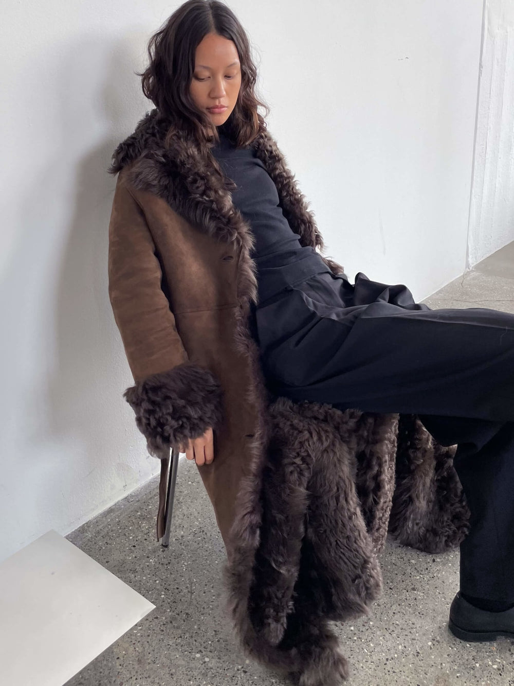 MEOTINE lang brun frakke med pelskrave og lommer, perfekt til stilfulde vinterdage.