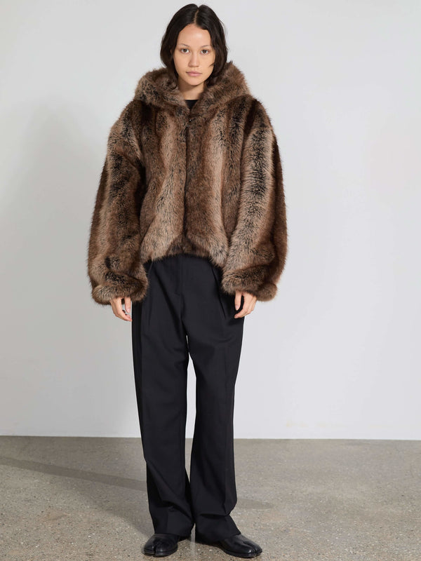 Lækker MEOTINE pelsjakke med hætte, i brun nuancer, kombineret med sorte bukser for et stilfuldt look.