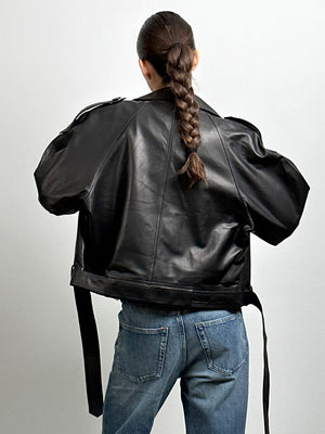 Sort læderjakke fra MEOTINE set bagfra, med en løs pasform og detaljerede skuldre, parret med blå jeans.