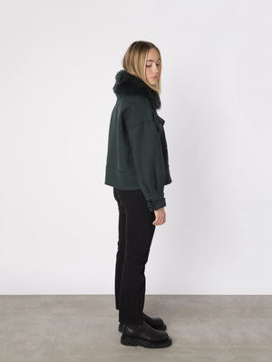 Grøn jakke med pelskrave fra MEOTINE, bæredygtig og stilfuld, perfekt til kolde dage. Model står i profil.