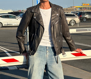 Læderjakke fra MEOTINE, stilfuld og moderne, kombineret med en hvid t-shirt og løse jeans i en urban setting.