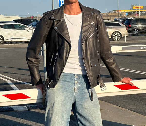 Læderjakke fra MEOTINE, stilfuld og moderne, kombineret med en hvid t-shirt og løse jeans i en urban setting.