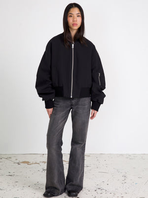 Sort bomberjakke med bredde og lynlås, parret med grå flared jeans. MEOTINE tilføjer et moderne touch til din garderobe.