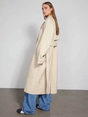 Lang beige trenchcoat med oversize pasform, bæltedetalje og slidser, perfekt til en moderne og stilfuld look fra MEOTINE.