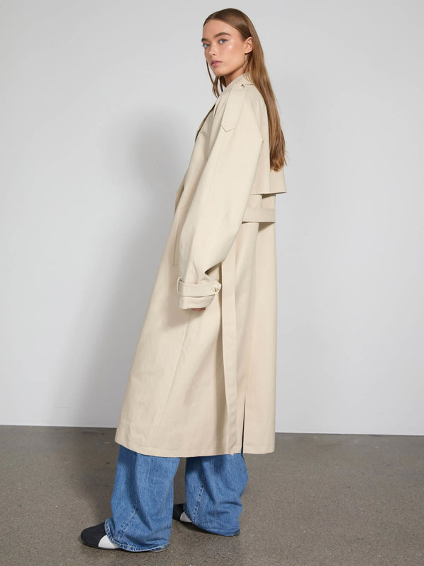 Lang beige trenchcoat med oversize pasform, bæltedetalje og slidser, perfekt til en moderne og stilfuld look fra MEOTINE.